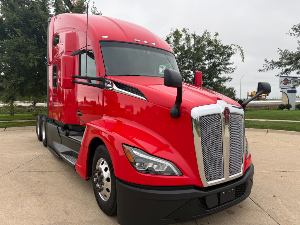 Kenworth T680 sleeper cab truck in red, front-left view, with large chrome grille and black bumper, daytime.