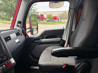 Kenworth T680 cab interior view showing steering wheel, dash, and driver seat with window and side mirror.