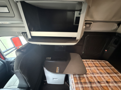 Kenworth T680 interior sleeper cab with open overhead storage and a fold-out table.
