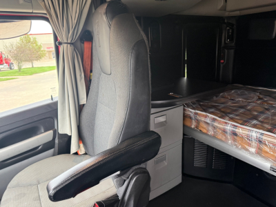 Kenworth T680 sleeper cab interior showing driver's seat, overhead cabin with bed, and storage drawers.