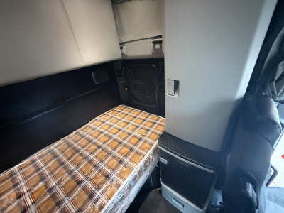 Kenworth T680 sleeper cab interior with plaid mattress, storage compartments, and side panel.