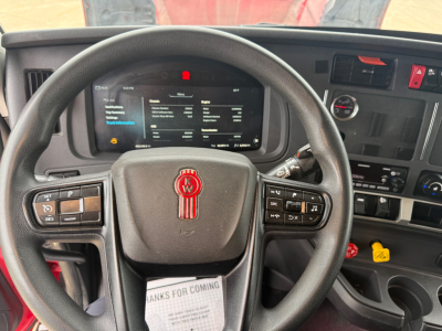 Kenworth truck interior steering wheel with dashboard display and controls; visible text on screen and buttons.