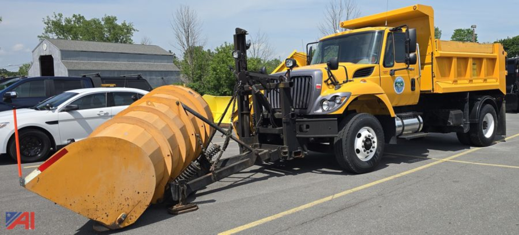 International WorkStar 7500 dump truck with front plow and snow bucket attachment in a parking lot.