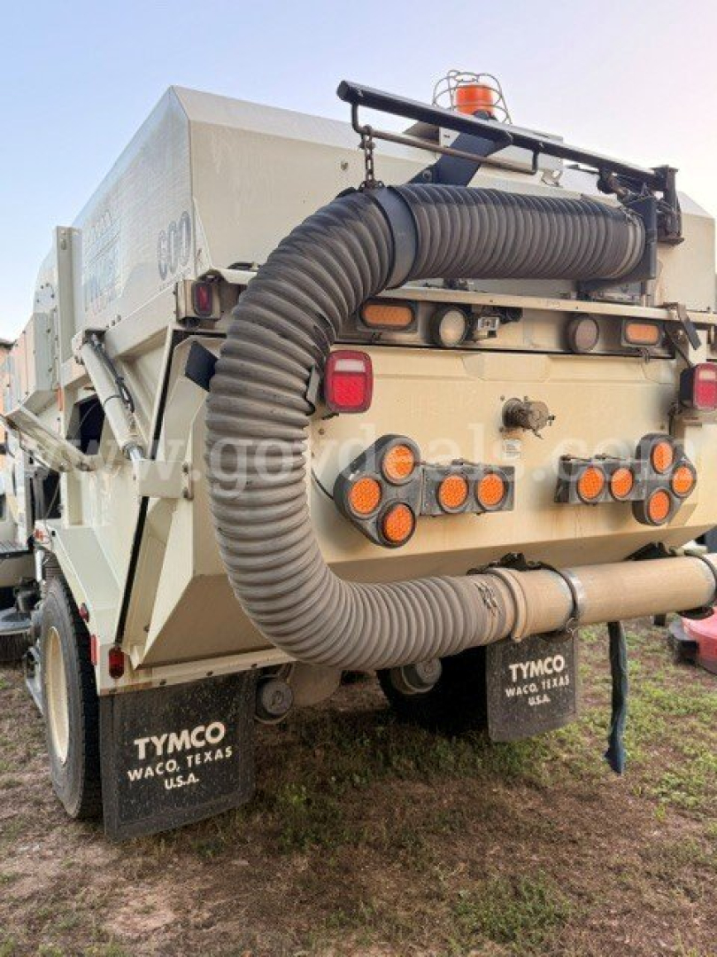 Dump truck rear showing large flexible vacuum hose and multiple circular ports; taillights and mud flaps; TYMO mud flaps in Waco, Texas; orange beacon on top.