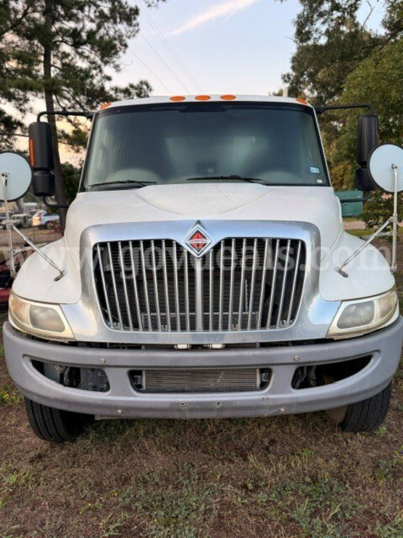Front view of a white 2016 International 4300 dump truck showing large chrome grille, headlights, bumper, and side mirrors.