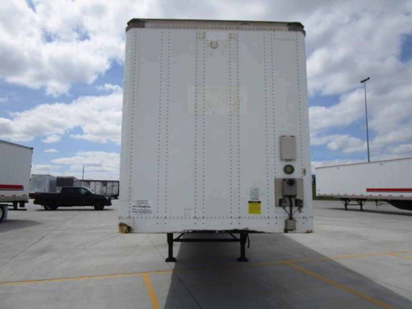 Rear view of a white 2014 Stoughton van trailer showing a raised platform, door hardware, and a small utility box with labels on the right side.