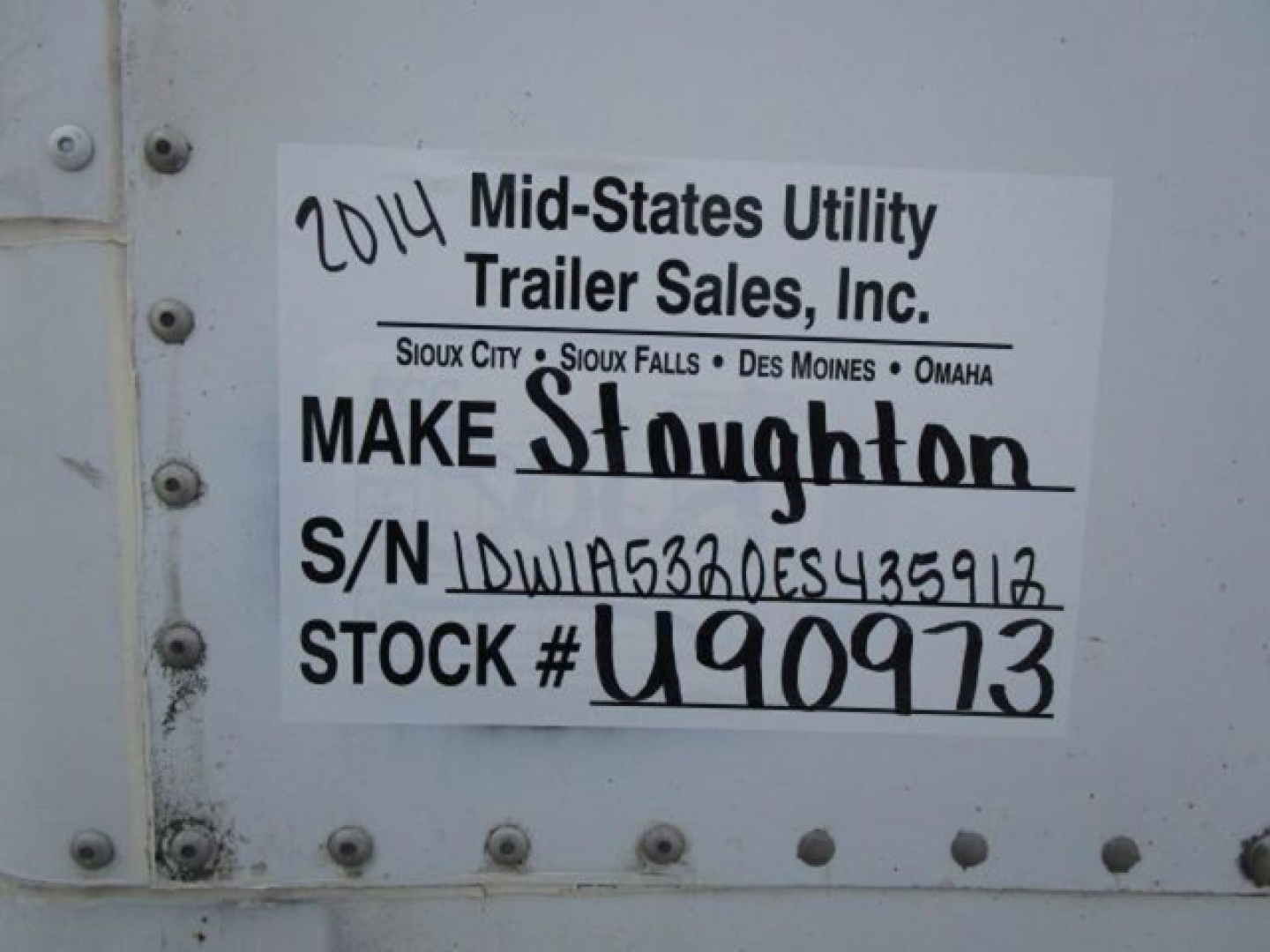 Vehicle trailer door with a label: '2014 Mid-States Utility Trailer Sales, Inc.' Make Stoughton, S/N 1DW1A5320ES435912, STOCK # U90973, handwritten '2014' and other details.