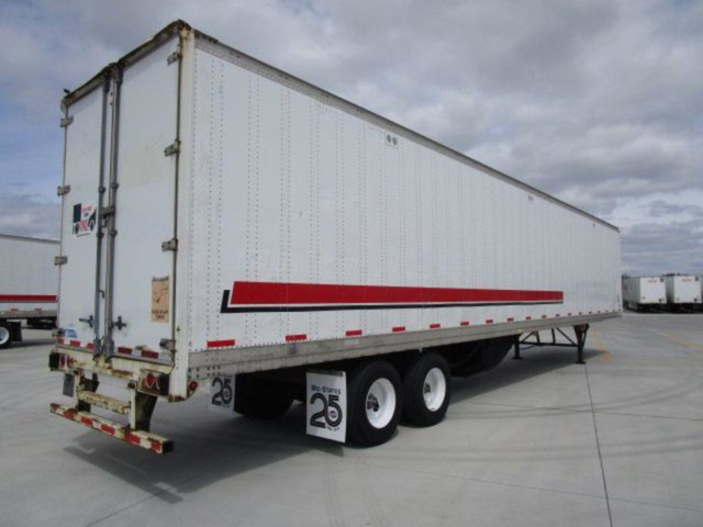 Stoughton van trailer showing side and rear, white with red stripe, dual rear wheels, license plate area and rear doors.