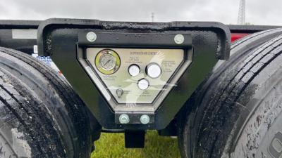 Trailer emergency/air gauge panel showing pressure gauges and control dial; triangular panel with labels and knobs between dual tires.