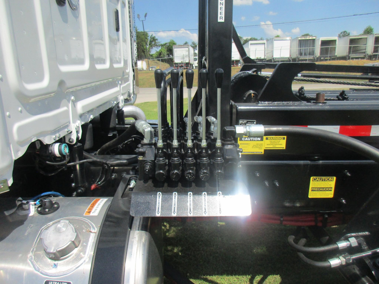 Trucks component view showing hydraulic levers and control panel on a Western Star 47X roll-off chassis with hydraulic lines and metal plate.