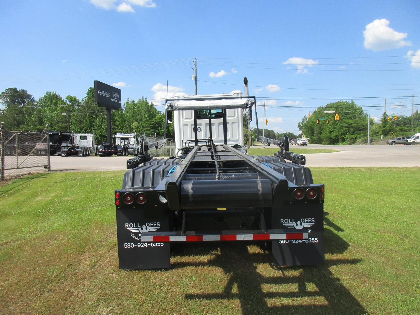 Western Star 47X roll-off truck rear view showing chassis and mud flaps with Roll Offs branding and contact numbers.