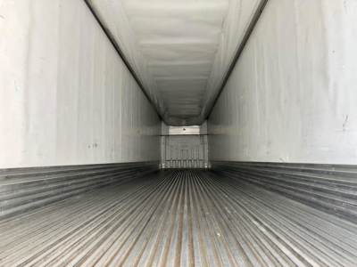 Trailer interior showing empty refrigerated trailer with ribbed floor and light at far end; long narrow cargo bay