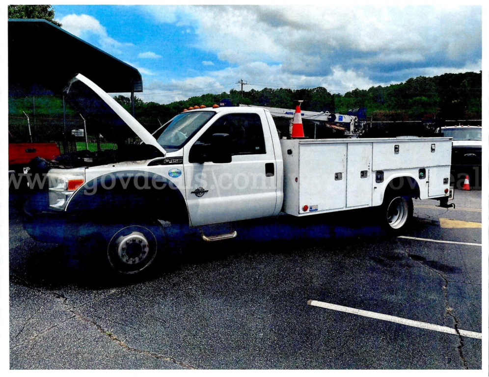 Ford F-450 service truck with open hood in a parking lot, service body with multiple compartments