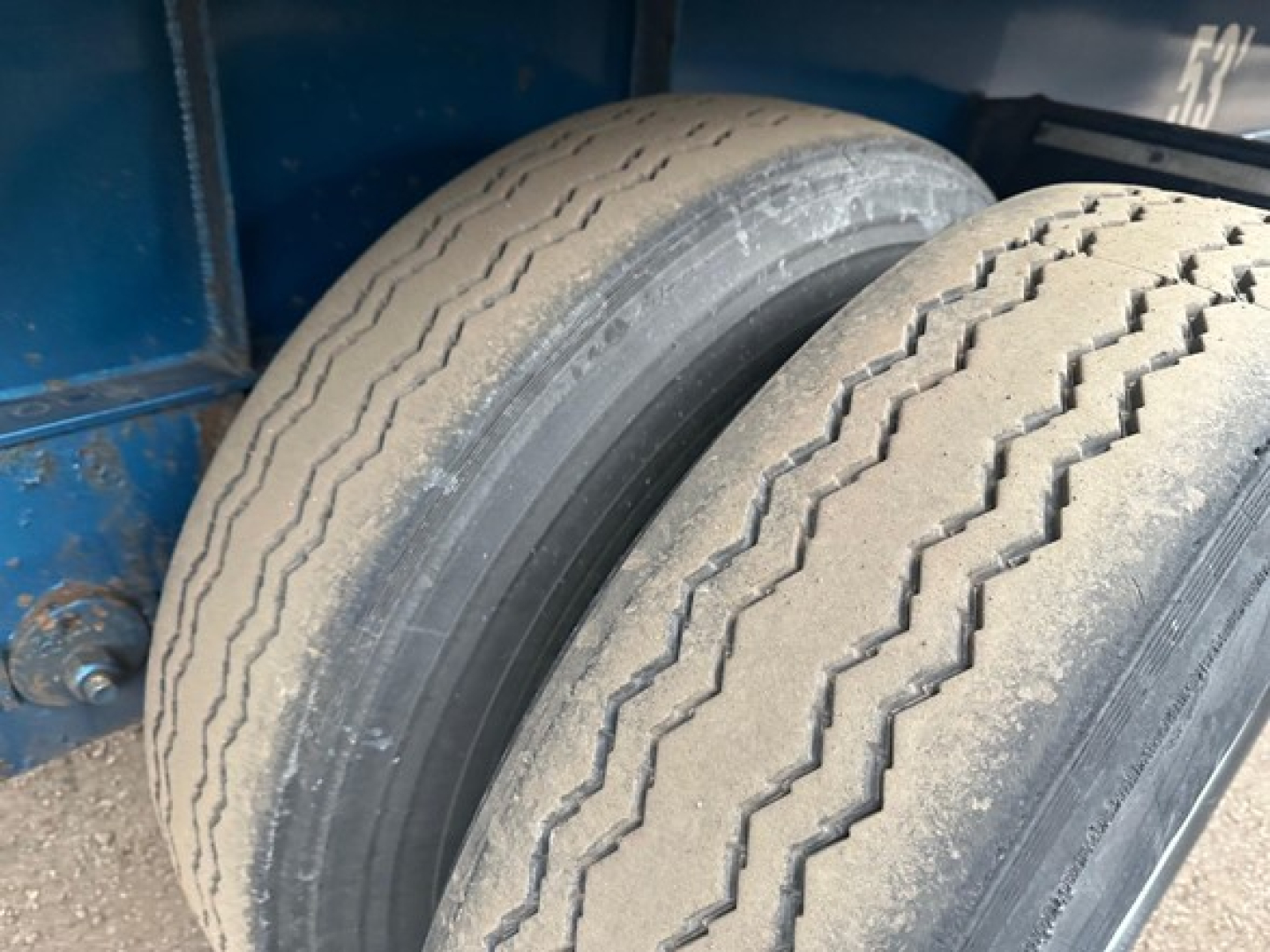 Great Dane trailer dual tires in the wheel well showing tread details and blue frame.