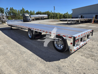 Trailer showing a long aluminum dropdeck flatbed with rear ramps, dual rear axles, chrome wheels, and reflective side markings.