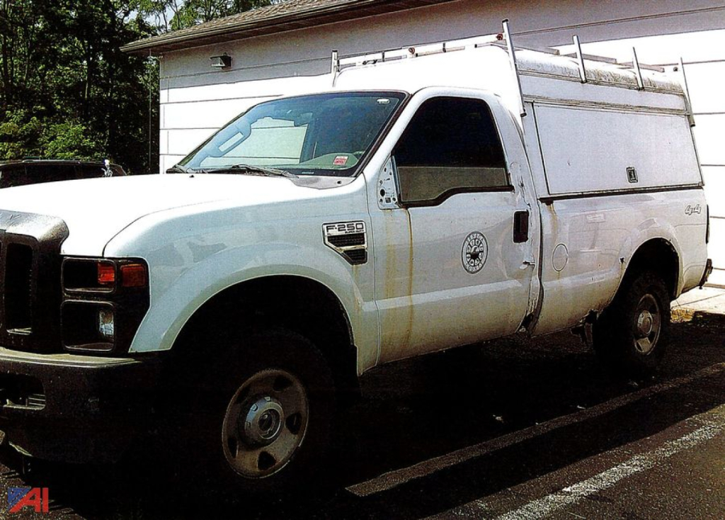 Ford F-250 XL Super Duty pickup truck with utility box and ladder rack, side view showing white body and worklogo on door.