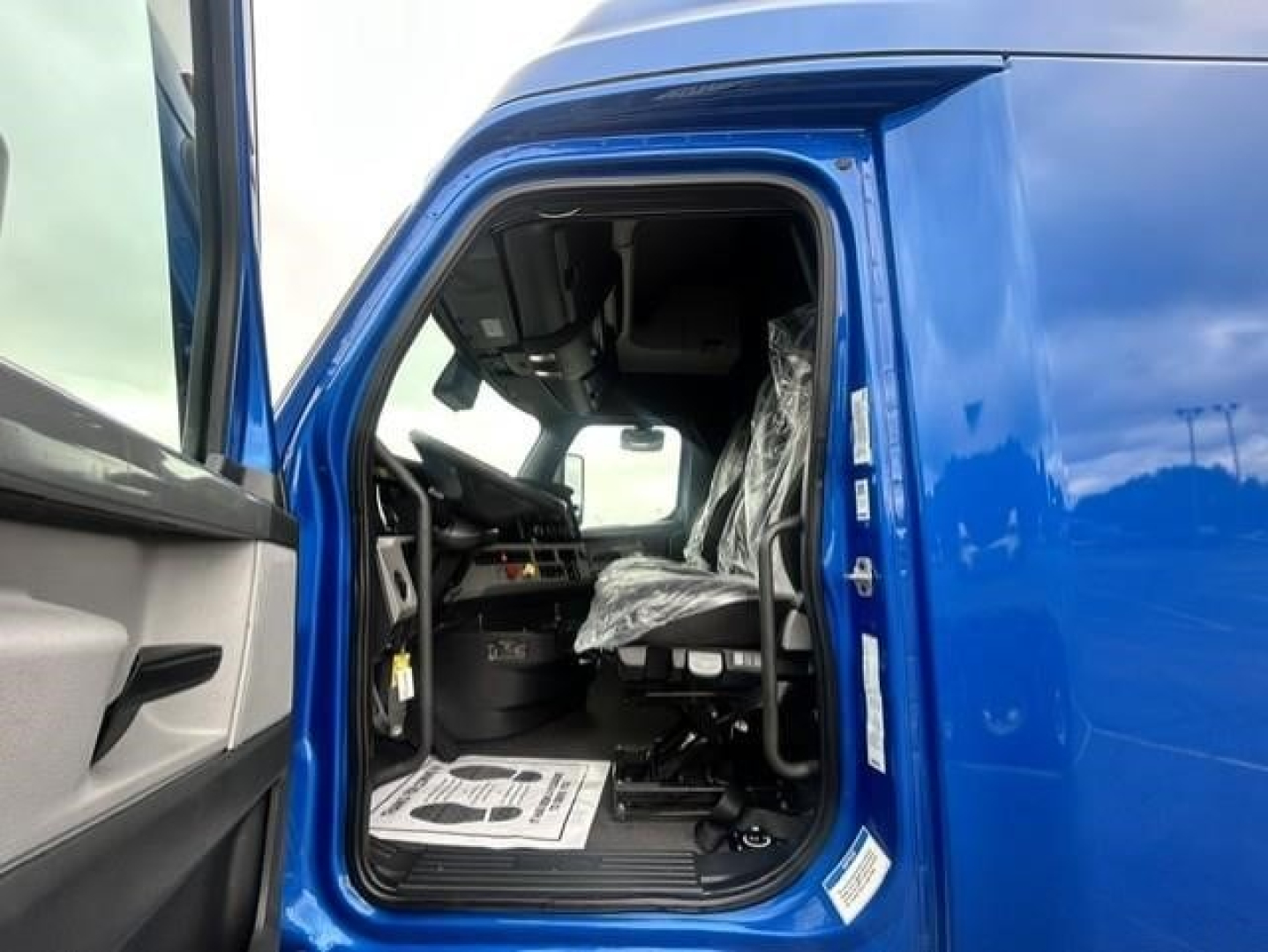 Freightliner Cascadia 126 cab interior view from open door showing driver seat and dashboard.