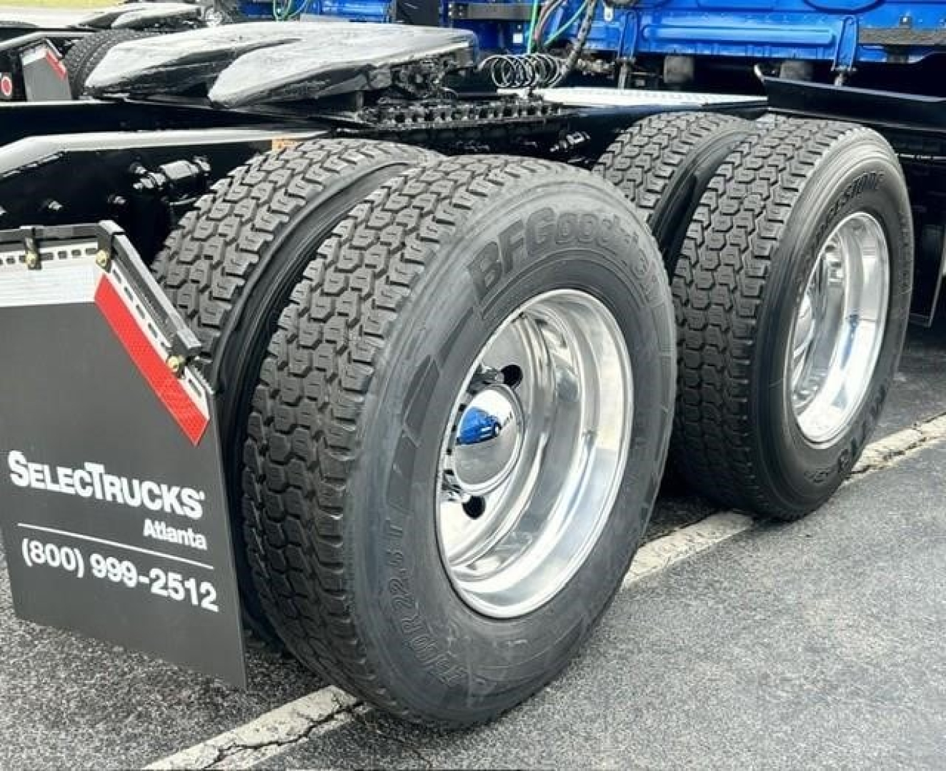 Freightliner Cascadia 126 trailer wheels and dual rear tires visible, chrome rims, part of truck undercarriage, wheel tags and mudflap with Selectriucks Atlanta and phone number.