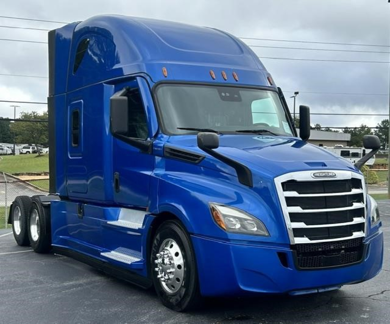 Blue Freightliner Cascadia 126 tractor from front-left side with sleeper cab and chrome accents.
