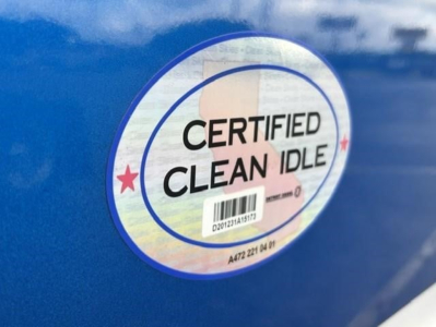 Sticker label reading CERTIFIED CLEAN IDLE with barcode on blue truck exterior.