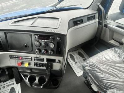 Dashboard of a Freightliner Cascadia 126 sleeper cab showing controls, climate dials, and cup holders.