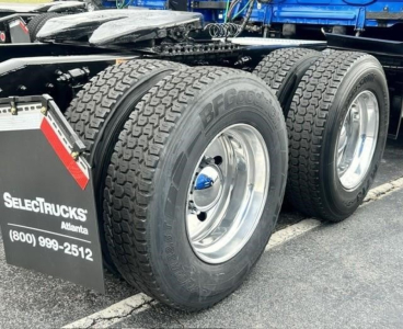 Freightliner Cascadia 126 trailer wheels and dual rear tires visible, chrome rims, part of truck undercarriage, wheel tags and mudflap with Selectriucks Atlanta and phone number.