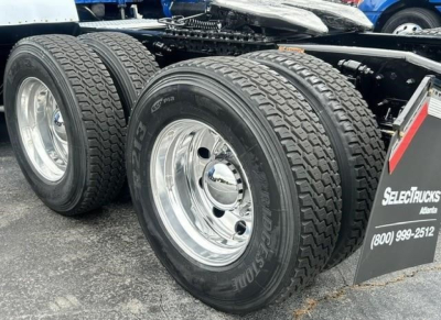 Truck axle view showing dual rear wheels with Bridgestone tires and chrome rims on a Freightliner Cascadia 126 chassis.