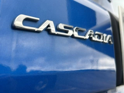 Vehicle badge reading CASCADIA on blue Freightliner Cascadia cab side with chrome letters