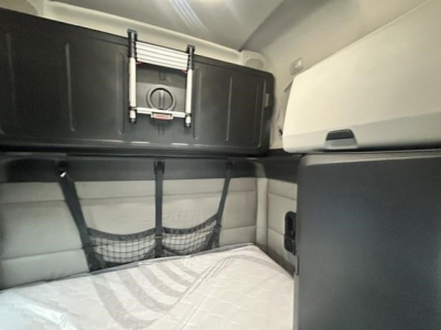 Freightliner Cascadia interior sleeper area with storage bunk, net pocket, and overhead cabinet, cab design visible.