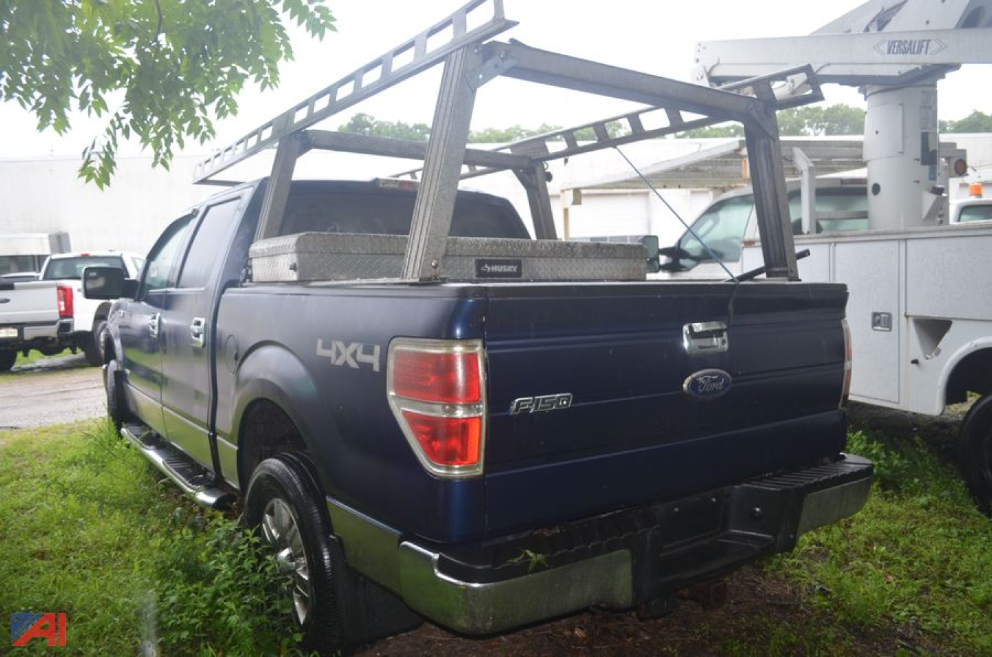 Ford F-150 pickup with 4x4 badge, crew cab, blue exterior, rear view showing truck bed and overhead ladder rack, 2011 model year label visible