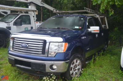 2011 Ford F-150 Crew Cab 4x4 pickup truck in blue with chrome grille and bumper, front three-quarter view.