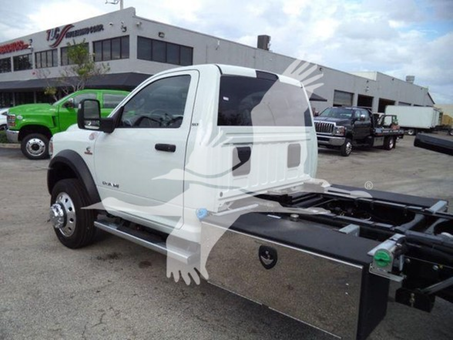 Ram 5500 cab showing side view with rollback chassis and chrome toolbox on the side, white exterior, black tires, dealership lot in background.