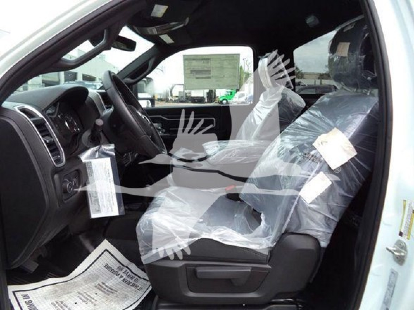 Ram 5500 SLT interior showing black dashboard, steering wheel, driver and front passenger seats with plastic coverings; tags hang from mirror and seat.