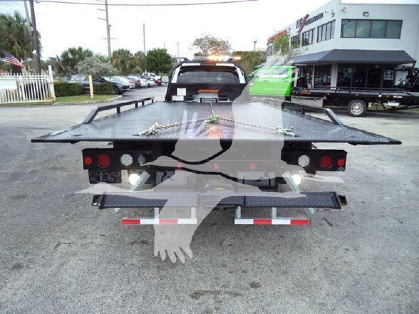 Ram 5500 rollback truck viewed from rear with flatbed and towing lights; license plate area not visible; dealership lot in background.