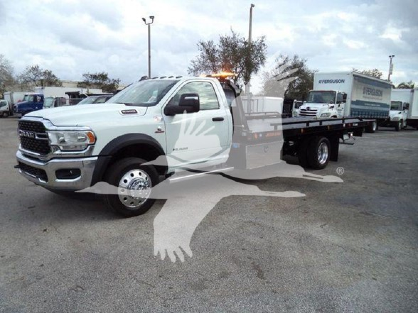 Ram 5500 rollback tow truck in white with flatbed, side view showing front grille and 'RAM' branding.