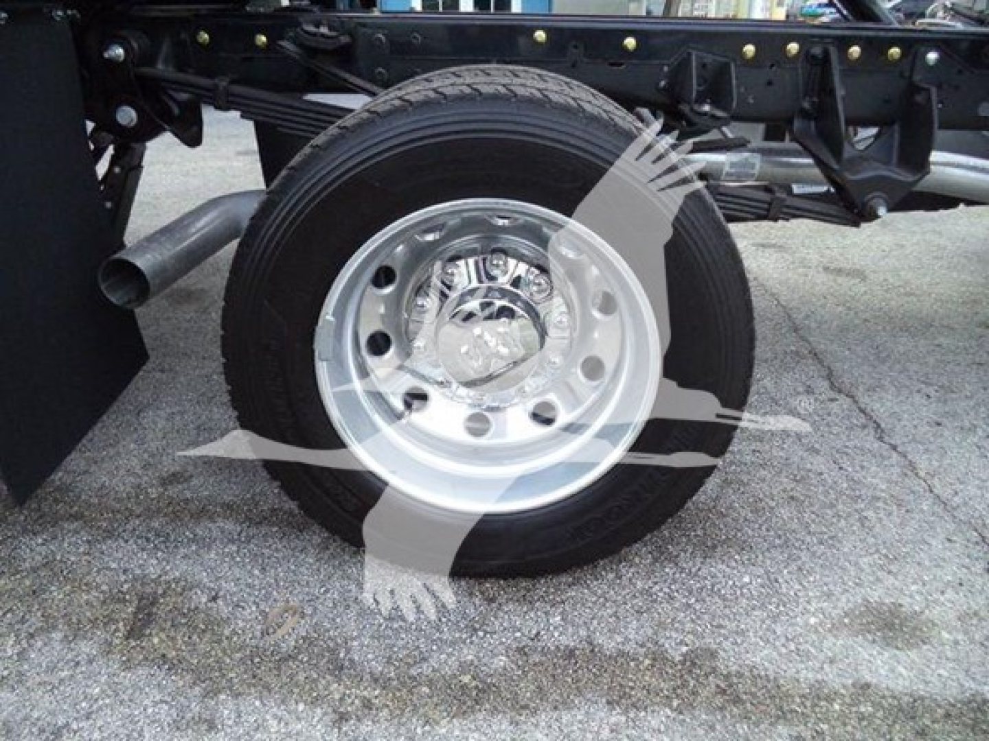 Truck wheel and suspension detail on Ram 5500 rollback chassis showing polished steel wheel and black chassis components.