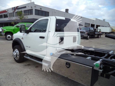Ram 5500 cab showing side view with rollback chassis and chrome toolbox on the side, white exterior, black tires, dealership lot in background.