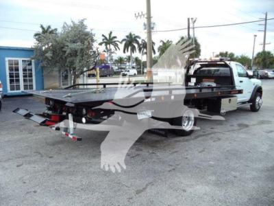 Ram 5500 rollback tow truck flatbed with yellow toolbox and lettering in background.
