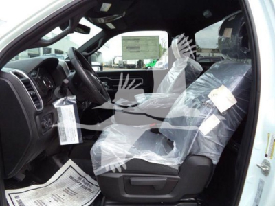 Ram 5500 SLT interior showing black dashboard, steering wheel, driver and front passenger seats with plastic coverings; tags hang from mirror and seat.