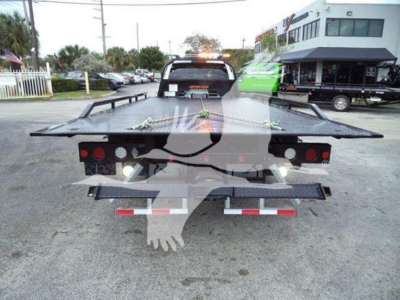 Ram 5500 rollback truck viewed from rear with flatbed and towing lights; license plate area not visible; dealership lot in background.