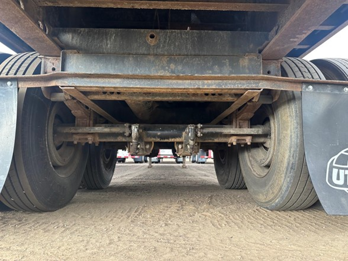 Underside view of a Fontaine Velocity trailer showing axle assembly and suspension components, rugged steel frame, dual tires on each side, and mud flaps.