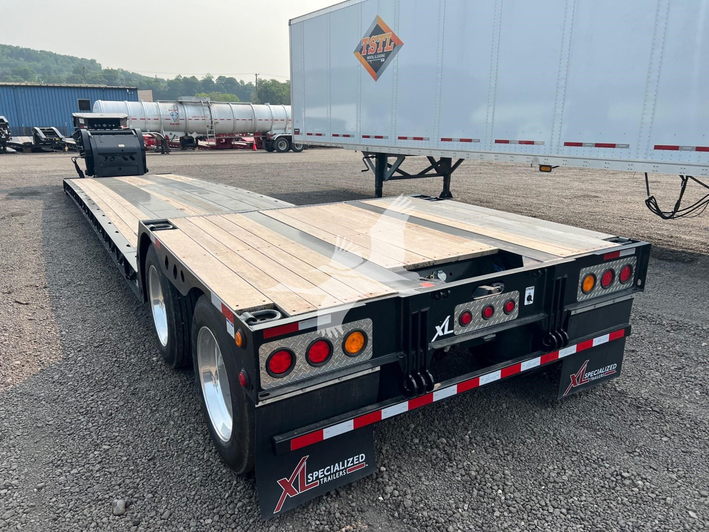 XL Specialized XL80HD Trailer in yard with flatbed deck and dual rear axles.