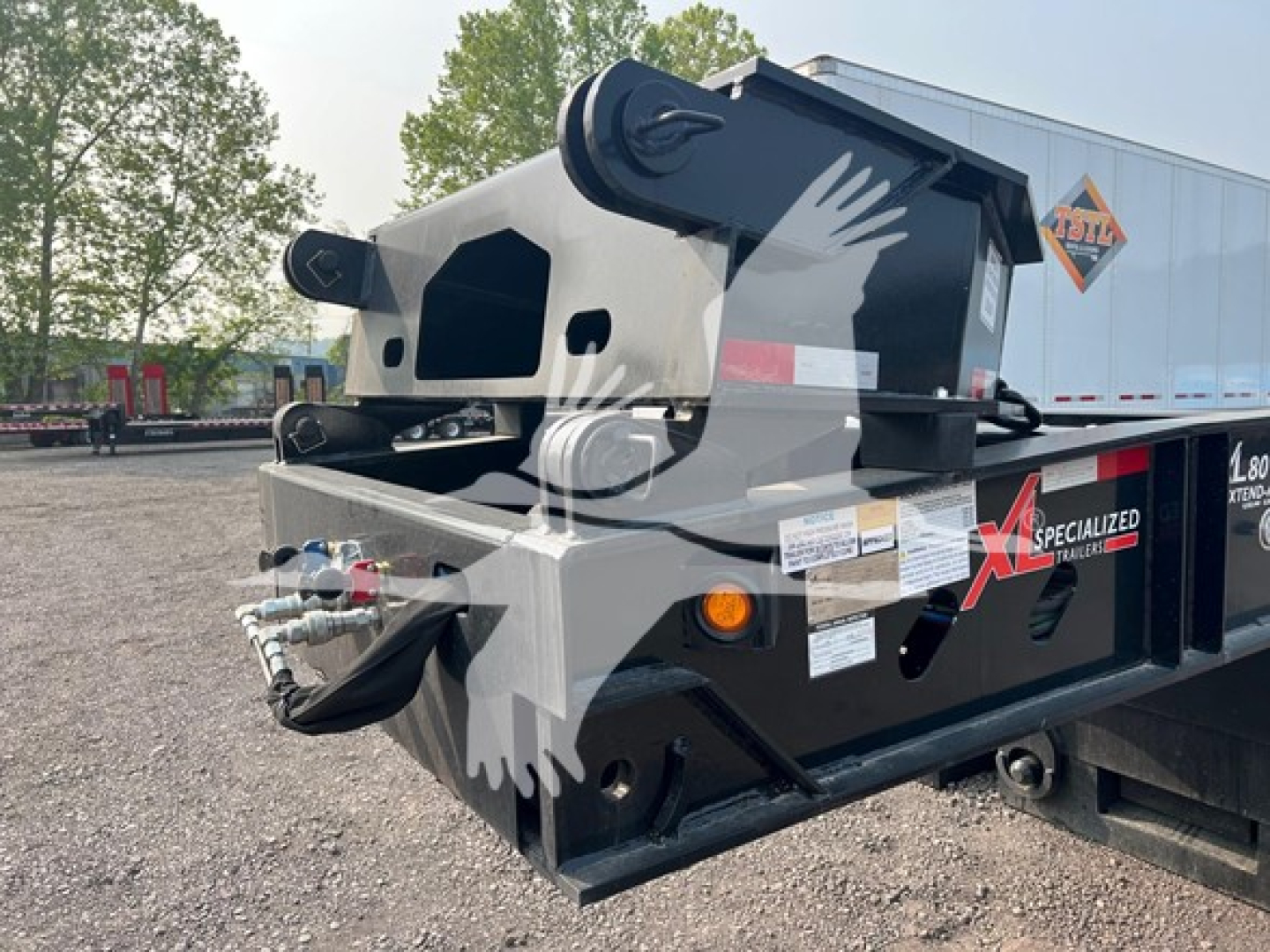 Trailer hitch and hydraulic boom on XL Specialized XL80HDE lowboy trailer showing hydraulic hoses and frame details.
