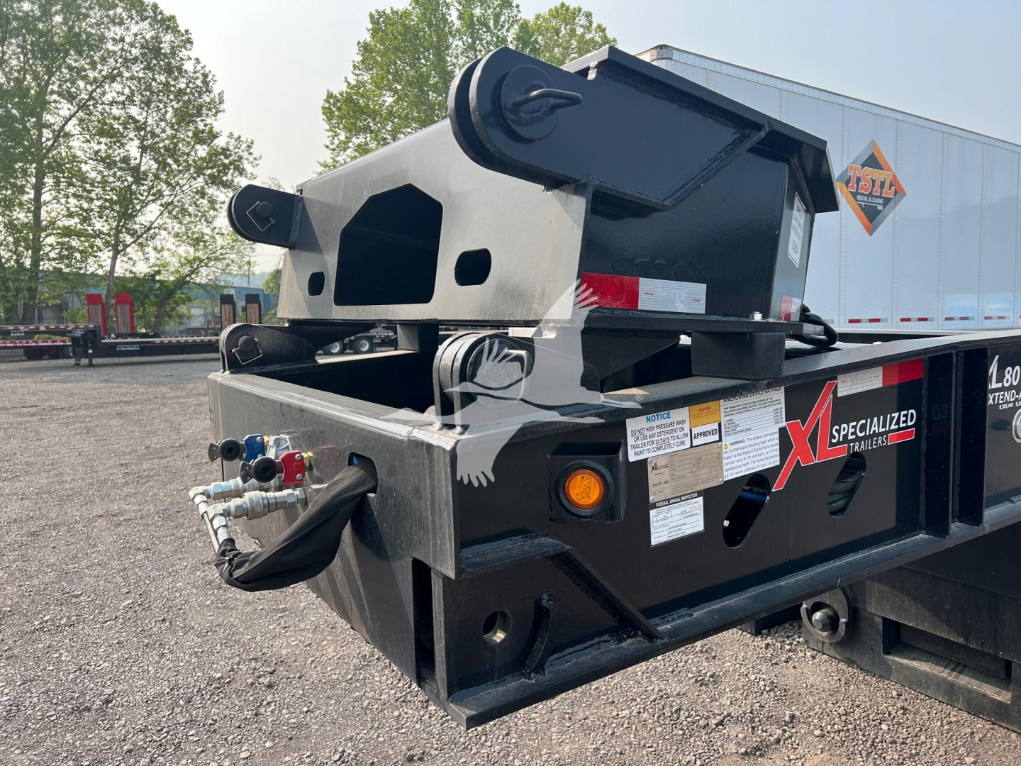 Trailer hitch and rear end of 2024 XL Specialized XL80HDE lowboy trailer showing black steel frame, hydraulic controls, and labeling.