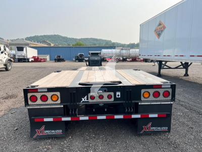 Lowboy trailer rear view showing wooden deck, taillights, and mud flaps with XL Specialized branding.