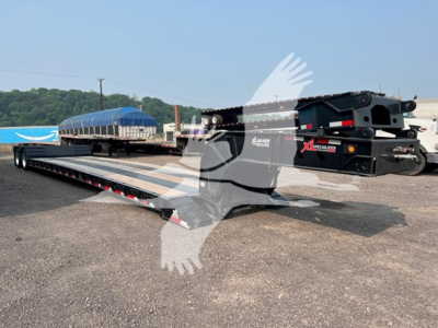 Lowboy trailer in yard showing XL Specialized XL80HD E80 base with hydraulic gooseneck and long flat deck, side rails, and blue tarped load in background.
