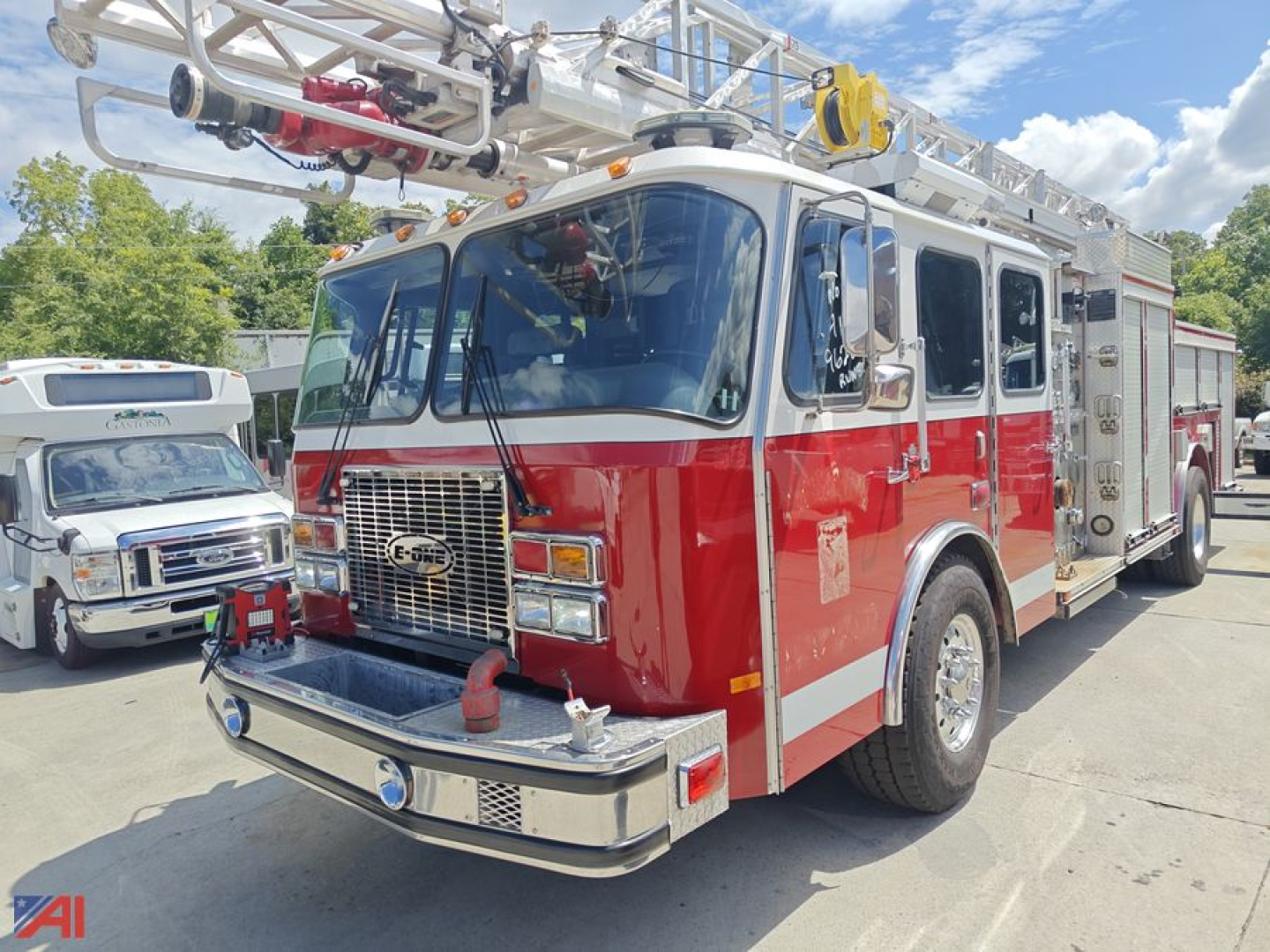 Fire engine truck with a red and white Quint Ladder setup, front grille, chrome bumper, and aerial ladder on top; clear blue sky.