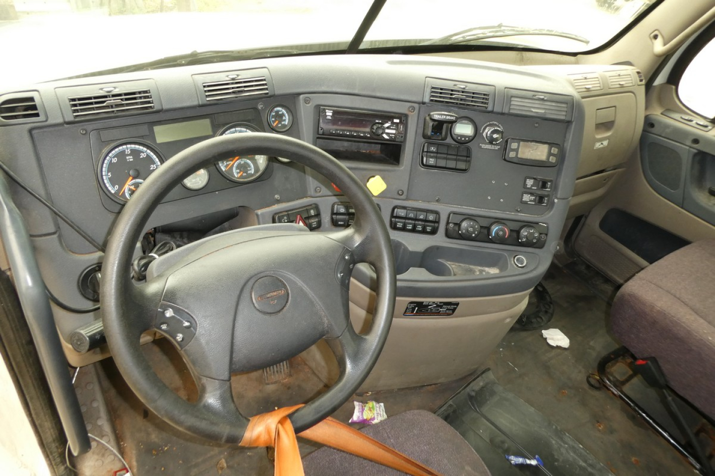 Cab interior of a Freightliner Cascadia 125 truck showing steering wheel, dashboard with gauges, center console, and multiple controls.