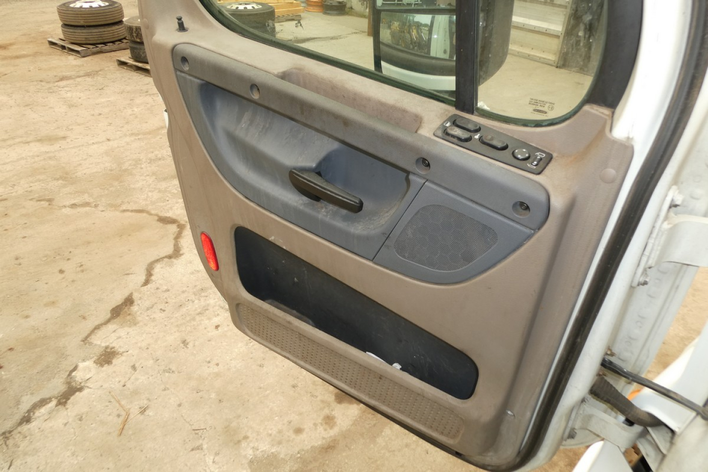 Truck door interior panel showing window controls and storage pocket inside a Freightliner Cascadia cab door