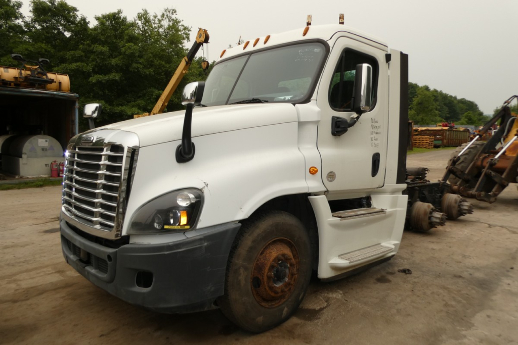 Truck cab showing Freightliner Cascadia 125 daycab with white exterior and front grille, stock number placard, VIN 3AKJGEDR7JSJW0475.